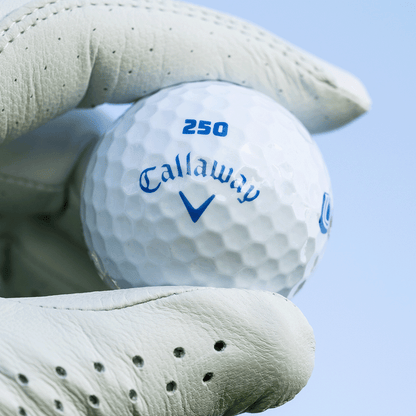 Gloved hand holding a Callaway Supersoft USA 250 golf ball