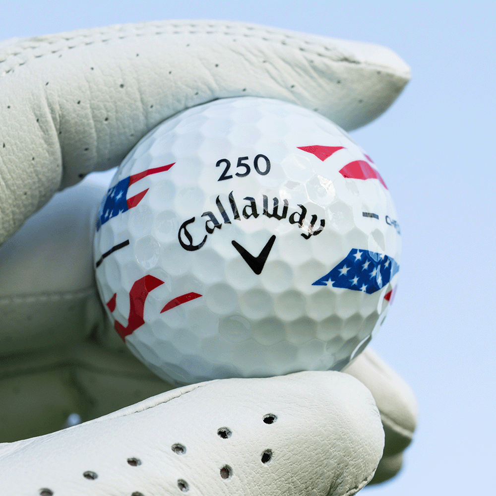 Gloved hand holding a Callaway Chrome Tour USA Stripe golf ball with 250 number